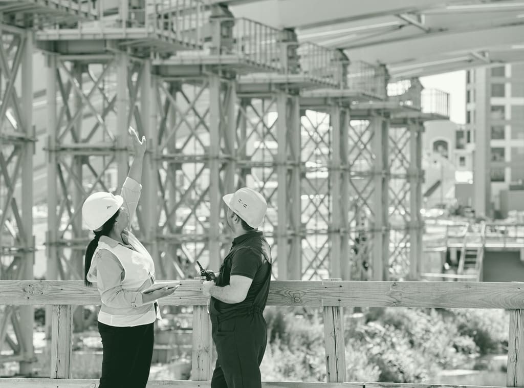 A supervisor and a site engineer on a walkway, one pointing up at falsework towers above them